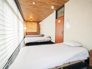 zwei Betten in einem kleinen Zimmer mit zwei Drittelsitzungen in der Unterkunft E E House in Numazu