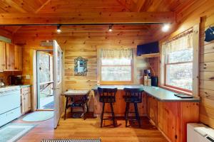 a log cabin kitchen with a counter and stools at Lenas in Waterville +30 photos