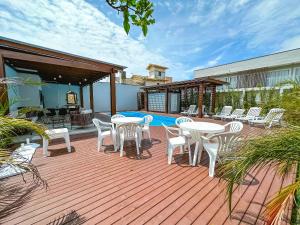 a deck with tables and chairs next to a pool at Condomínio Brises Downtown Garopaba in Garopaba
