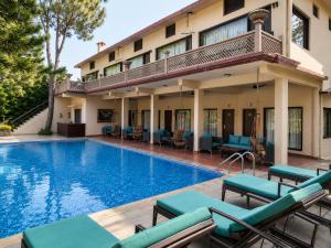 a hotel with a swimming pool in front of a building at Bel-La Monde Riverside Jim Corbett - "A Unit of Luxe Opera Hotels & Resorts" in Garjia