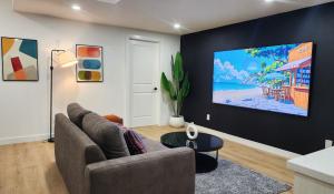 a living room with a couch and a tv on a wall at TNC Stays Luxurious Modern Suite Seton Calgary South in Calgary