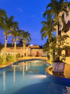 a swimming pool with palm trees and lights at Miu Homestay Hue in Thôn Lại Thê