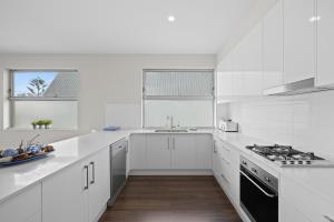 a white kitchen with a sink and a stove at Meander - Port Noarlunga South - C21 SouthCoast Holidays in Port Noarlunga South