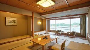 a living room with a table and a large window at Hotel Urashima in Katsuura