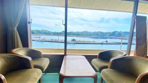 a room with chairs and a view of a river at Hotel Urashima in Katsuura