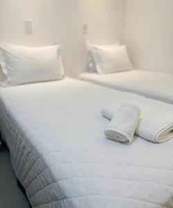two white beds with white sheets and pillows at Pousada Areias do Pero in Cabo Frio