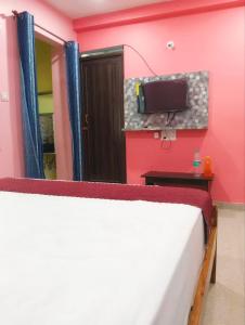a bedroom with a bed and a tv on the wall at BHS Deluxe Rooms in Puri +28 photos
