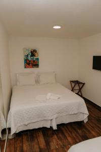 a bedroom with a white bed with two towels on it at Pousada Areias do Pero in Cabo Frio