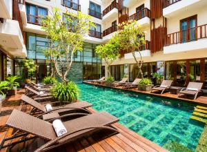 a hotel swimming pool with lounge chairs and a resort at d'primahotel Seminyak in Seminyak