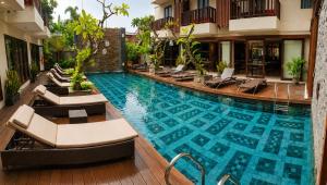 a large swimming pool with lounge chairs in a hotel at d'primahotel Seminyak in Seminyak