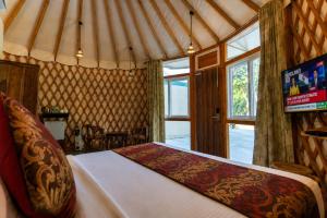 a bedroom with a bed and a tv in a tent at Bel-La Monde Riverside Jim Corbett - "A Unit of Luxe Opera Hotels & Resorts" in Garjia