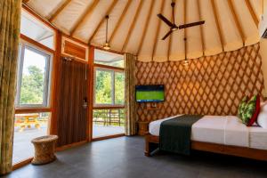 a bedroom with a bed and a tv on a wall at Bel-La Monde Riverside Jim Corbett - "A Unit of Luxe Opera Hotels & Resorts" in Garjia +174 photos