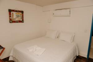 a white bed with white sheets and pillows in a room at Pousada Areias do Pero in Cabo Frio +30 photos