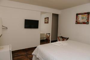 a white room with two beds and a flat screen tv at Pousada Areias do Pero in Cabo Frio