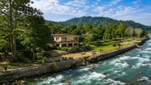 a house on the banks of a river at Bel-La Monde Riverside Jim Corbett - "A Unit of Luxe Opera Hotels & Resorts" in Garjia