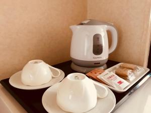 a coffee maker and two cups and plates on a counter at Shakespeare Hotel in Hakuba