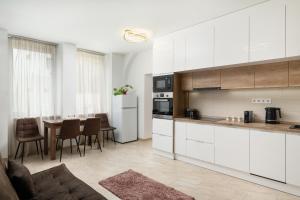 a kitchen with white cabinets and a table with chairs at DowntownKate in Debrecen