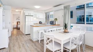 a kitchen and dining room with a white table and chairs at Tripcony Quays Unit 11 in Caloundra
