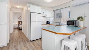 a kitchen with a white refrigerator and white cabinets at Tripcony Quays Unit 11 in Caloundra