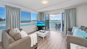 a living room with a couch and a tv and a table at Tripcony Quays Unit 11 in Caloundra
