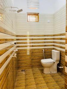 a bathroom with a toilet and wooden walls at Lotus Green Hotel And Restaurant in Arugam Bay