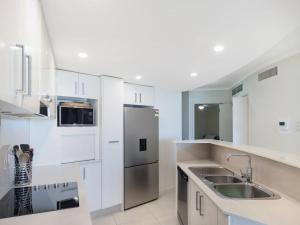 a kitchen with white cabinets and a stainless steel refrigerator at Points North Unit 507 - Caloundra in Caloundra