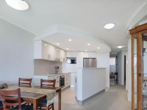 a kitchen with white cabinets and a table and chairs at Points North Unit 507 - Caloundra in Caloundra