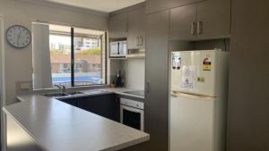 a kitchen with a refrigerator and a clock on the wall at Beachside Court Unit 9 in Caloundra