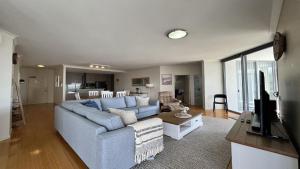 a living room with a blue couch and a tv at The Pinnacles Caloundra Unit 92 in Caloundra +9 photos