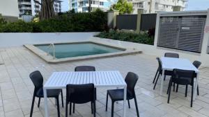 a patio with tables and chairs and a swimming pool at The Pinnacles Caloundra Unit 92 in Caloundra