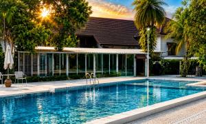 a swimming pool in front of a house with a building at Kenikar Raintree Resort Chumphon in Chumphon