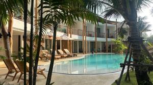 a swimming pool in front of a building with palm trees at The TALAY in Ban Na Tai
