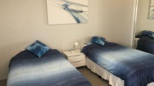 two beds in a room with blue sheets at Unit 33 Outlook Caloundra - Stunning Views! in Caloundra