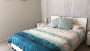a bedroom with a bed with a blue and white blanket at Unit 33 Outlook Caloundra - Stunning Views! in Caloundra