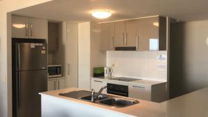 a kitchen with a sink and a refrigerator at Unit 33 Outlook Caloundra - Stunning Views! in Caloundra +7 photos