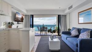 a living room with a blue couch and a view of the ocean at #812 Ramada Resort, Beachfront in Golden Beach