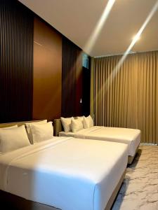 two beds in a hotel room with white sheets at Acasa Cottage by Samsara in Cipaok