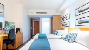 a hotel room with two beds and a desk at Lovely Studio Apartment Overlooking Golf Course! in Pelican Waters