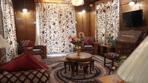 a living room with chairs and a table and a tv at Houseboat Saleem in Dal Lake