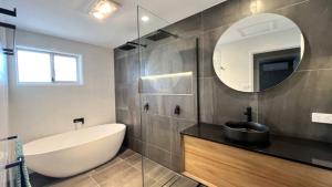 a bathroom with a tub and a sink and a mirror at Beachside Bliss In The Crown in Kawana Waters