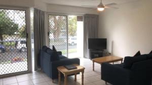 a living room with two blue couches and a tv at Windbourne Unit 8 in Golden Beach