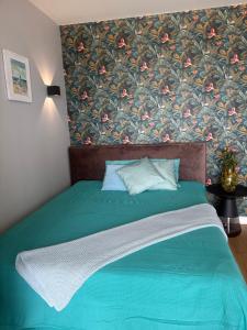 a bedroom with a green bed with a floral wallpaper at Apartamenty Laguna Przy Latarni in Darlowko