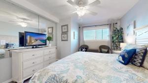 a bedroom with a bed with a television and a dresser at Summit 1013 in Panama City Beach