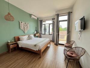 a bedroom with a bed and a television and a chair at Hue Sweethouse 2 Homestay in Hue