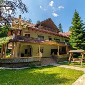a large yellow house with a grass yard at Cabana de la rau Satic in Sătic