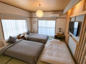 a room with two beds and a flat screen tv at DiDi Sakura 205 in Tokushima