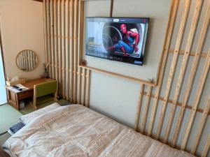 a bedroom with a bed and a tv on a wall at DiDi Sakura 205 in Tokushima