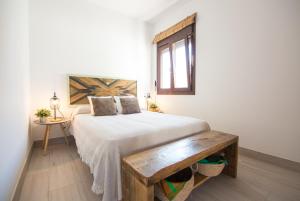 a bedroom with a bed and a wooden bench at Casa Poniente, encantadora casa de 2 dormitorios con jardín in Zahora