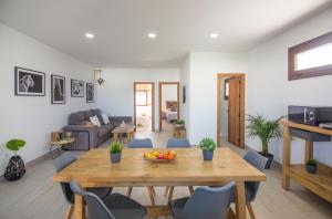 a dining room and living room with a wooden table at Casa Poniente, encantadora casa de 2 dormitorios con jardín in Zahora