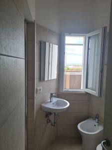 a bathroom with a sink and a toilet and a window at Le 2TORRI in Falconara Marittima